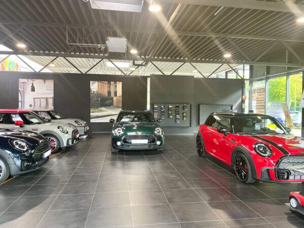 Innenansicht eines Autohauses mit mehreren ausgestellten MINI Cooper Fahrzeugen.